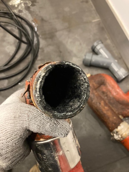 DrainFix HK 戴手套拎起崩咗嘅紅鑄鐵渠管末端